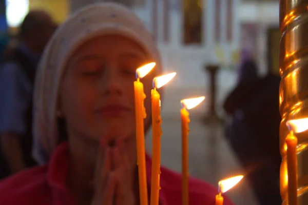 Een meisje in de kerk is bidden. Kaarsen in de tempel. Gebed tot God — Stockfoto