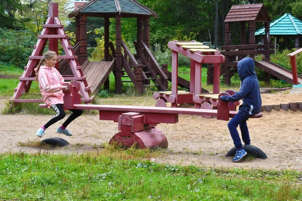 Latem dzieci huśtają się na drewnianym huśtawce. — Zdjęcie stockowe