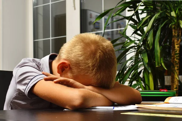 Школьник заснул за столом, делая домашнее задание. Уставший мальчик спит на столе . — стоковое фото
