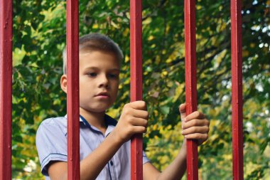 Çitin arkasındaki üzgün çocuk. Çocuklar parmaklıklar ardında. Ebeveynlik haklarından yoksun bırakılma.