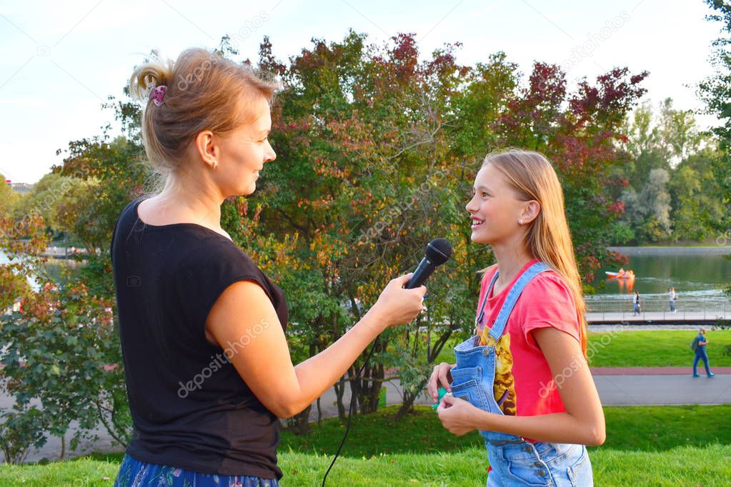 Interviewing girls. Television reporting in the park.