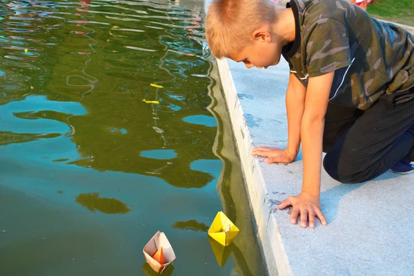 Anak itu meluncurkan kertas berwarna perahu di air mancur . — Stok Foto