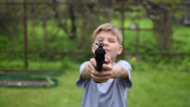 Het jongenskind uit een jachtgeweer richt zich op het doel buiten. jongen leert schieten. — Stockvideo
