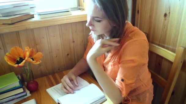 Donna con un libro in una casa di legno legge. Formazione a distanza . — Video Stock