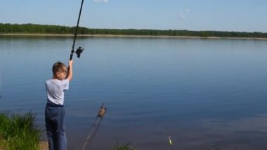 Oğlum balık tutmak için bir göletin kıyısında balık tutuyor. Çocuklar için balıkçılık hobileri...