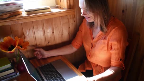Frau in Holzhaus spricht per Videochat auf Laptop. Online-Konsultation. — Stockvideo