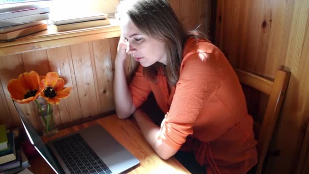 Женщина в деревянном доме разговаривает в видеочате на ноутбуке. Онлайн консультации . — стоковое видео