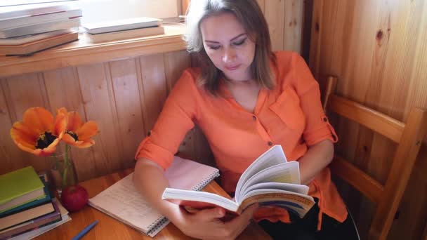 Donna con un libro in una casa di legno legge. Formazione a distanza . — Video Stock