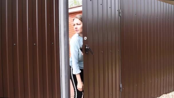 Nő kinyitja az ajtót, néz ki az utcára nem lát senkit, és becsukja az ajtót meglepetés. — Stock videók