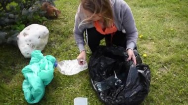 Kadın ve siyah çanta. Plastik şişeler açık havada.