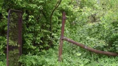 Terk edilmiş eski evlerin olduğu bir manzara. Açık kapılı, yabani otların olduğu çalılıklar.