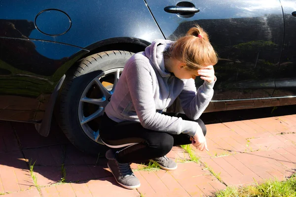 Une femme déprimée est assise près d'une voiture chère. La voiture ne démarre pas — Photo