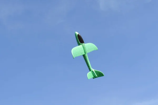Зелений іграшковий літак летить у блакитному небі. Відкрите небо для польоту — стокове фото
