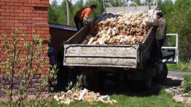 Adamlar köydeki bir evi ısıtmak için içinde ağaç olan bir kargo kamyonu boşaltıyor..