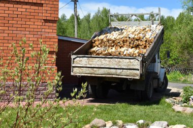 Kırsal yaşam için odun kırmış bir kamyon. Arabanın arkasında doğranmış kütükler var.
