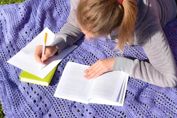 Una mujer escribe notas importantes de un libro de texto. estudiante se prepara para el examen . —  Fotos de Stock