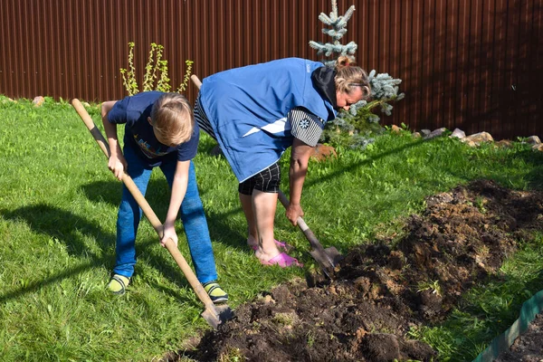 Mormor och sonson gräver jorden. Familj tillsammans vid stugan. — Stockfoto