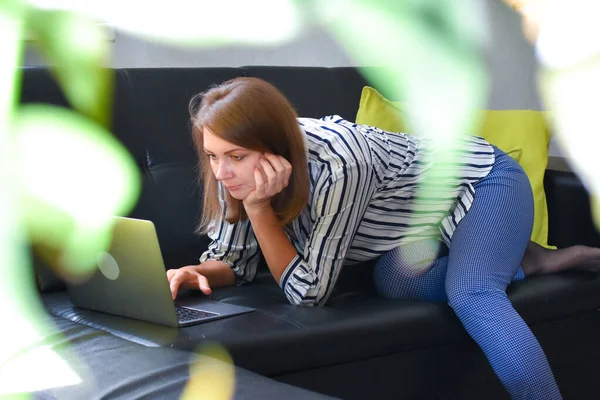 Donna con computer portatile lavora sul divano in appartamento — Foto Stock