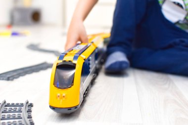 Bir apartmanda yerde demiryolu olan bir çocuk.