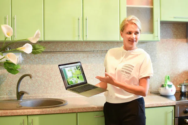 Chica interiorista en la cocina muestra el proyecto en la pantalla — Foto de Stock