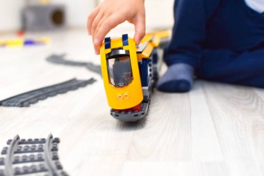 Anaokulunda oyuncak plastik trenle oynayan bir çocuk.