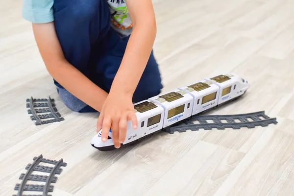 One boy is playing with a toy train on the floor. — Stock Photo, Image