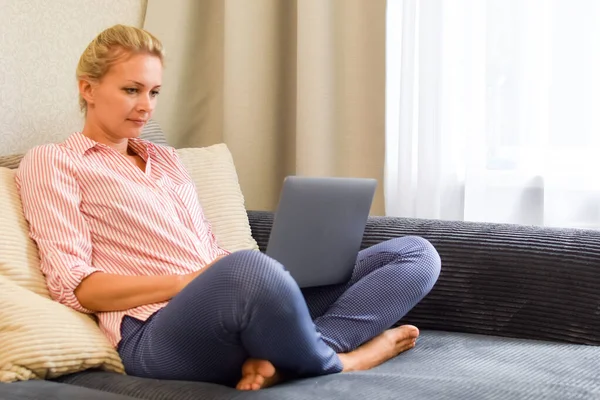 Жінка з комп'ютером на дивані працює. віддалений робочий фрілансер — стокове фото