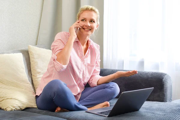 Trabalho remoto com laptop, mulher com telefone no sofá — Fotografia de Stock
