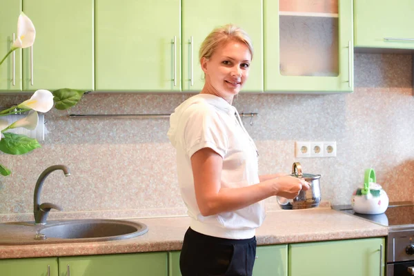 Красивая молодая женщина стоит дома на кухне с кастрюлей — стоковое фото