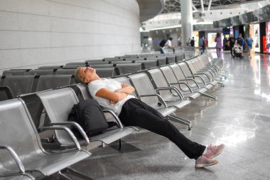 Genç bayan havaalanında bekleme odasında oturuyor. Uçuş gecikmesi