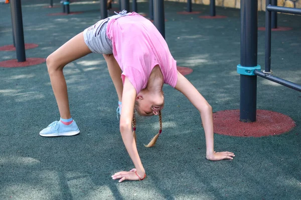 Kız köprü jimnastik egzersizinde duruyor. çocuğun spor aktiviteleri