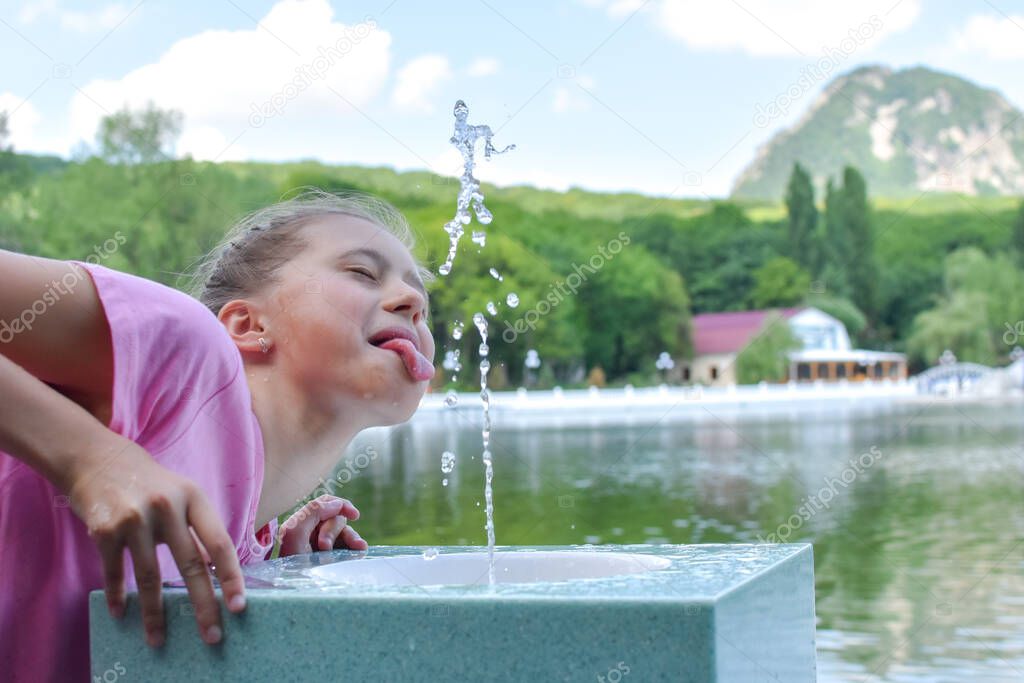 girl drinks clean water from a fountain. drinking public fountain with water