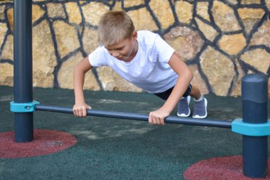 Erkek çocuk spor simülatöründe çalışıyor. Jimnastik egzersizleri. Çocuk çabaların üstesinden geliyor.