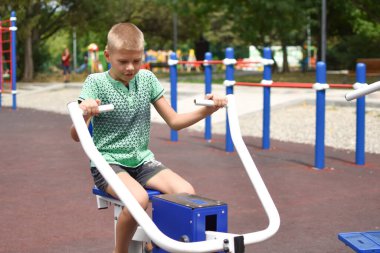 Erkek çocuk spor simülatöründe çalışıyor. Jimnastik egzersizleri. Çocuk çabaların üstesinden geliyor.