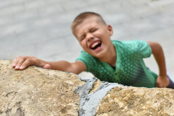 Risk of falling from mountain. child hangs on wall. dangerous games of children — Stock Photo, Image