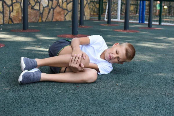 Дитячий спортсмен впав на землю. спортивне травмування ноги дитини . — стокове фото