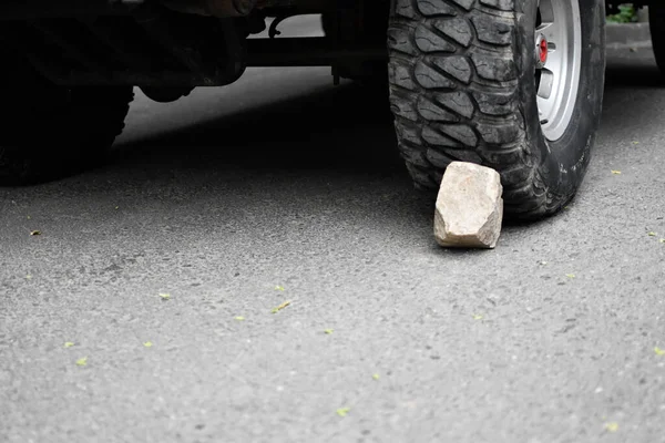 stone under the wheel of the car. wheel chock. parking on the mountain. danger of rolling off the vehicle