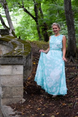 Uzun elbiseli güzel bir kadın ormanda tek başına yürüyor..