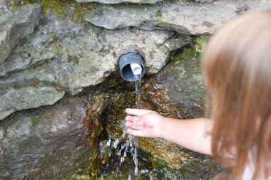 Küçük kız doğada temiz kaynak suyu içer..