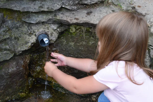 Klein meisje kind drinkt schoon bronwater in de natuur. — Stockfoto