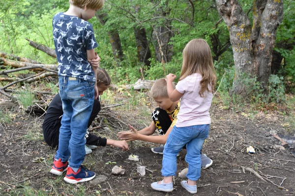 Группа детей туристов в лесу. Дети подливают масла в огонь. — стоковое фото