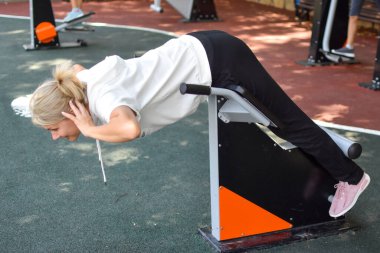 Bayan sporcu dışarıda oyun parkında egzersiz yapıyor. Sabah jimnastik eğitimi.