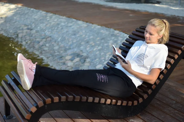 Mujer joven lee un libro en el parque afuera. — Foto de Stock