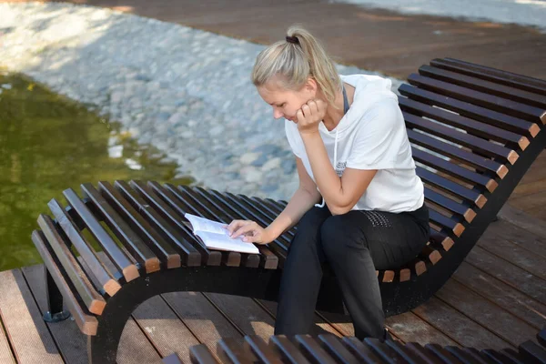 Молода жінка читає книгу в парку зовні . — стокове фото