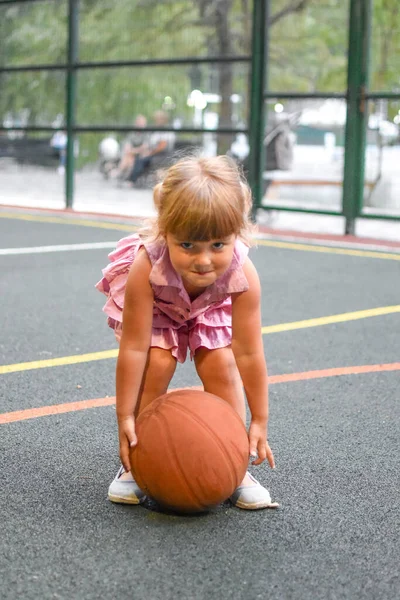 Забавная маленькая девочка с мячом на открытой площадке. Молодая милая спортсменка. — стоковое фото
