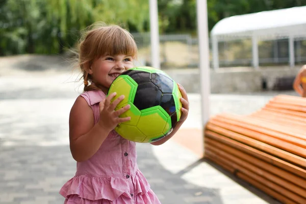 Gadis kecil lucu dengan bola di taman bermain luar ruangan. Gadis muda olahragawan cantik. — Stok Foto