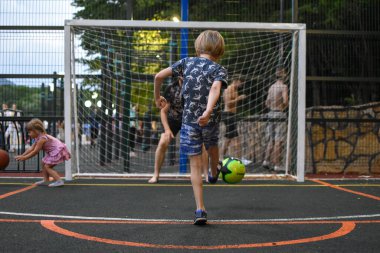 Baba ve çocuk açık hava spor sahasında futbol oynuyorlar. Bir ebeveyn küçük bir çocuğu eğitiyor..