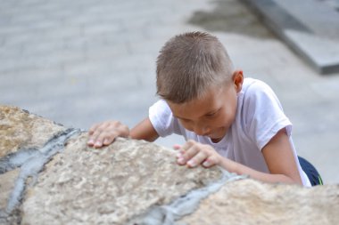 Çocuk çocuk zor engellerin üstesinden gelir. Yüksek bir dağa tırman.
