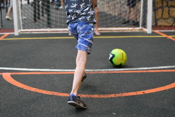 Baba ve çocuk açık hava spor sahasında futbol oynuyorlar. Bir ebeveyn küçük bir çocuğu eğitiyor..