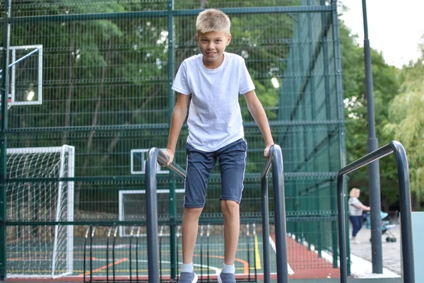 Junge beim Straßensport macht Turnübungen. Stadtsportplatz. — Stockfoto